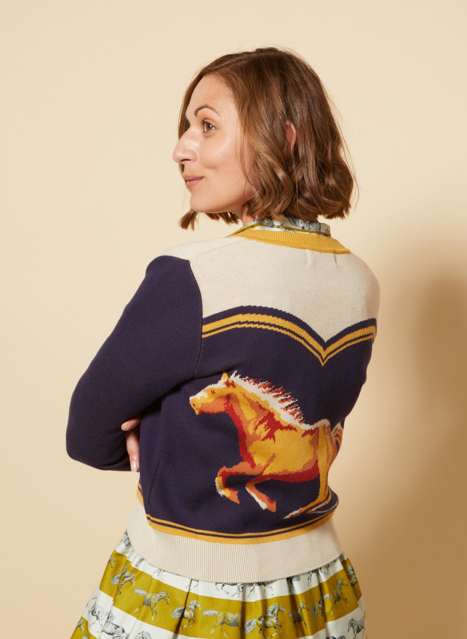 vintage style organic cotton knit cardigan in navy, white, and mustard with horse in the back