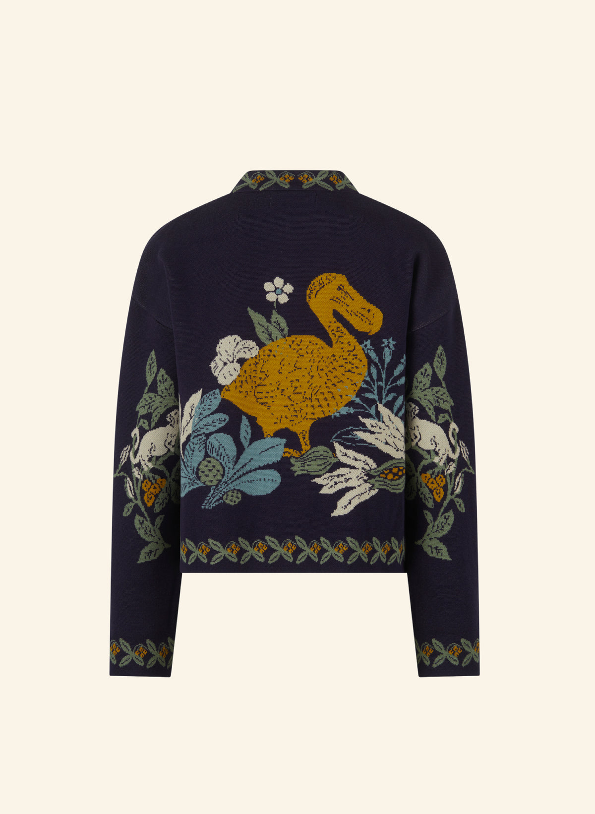 A cropped navy blue cardigan featuring vertical and horizontal floral and dodo embroidery in green, orange, and beige along the collar, front opening, and cuffs, displayed against a solid cream background.