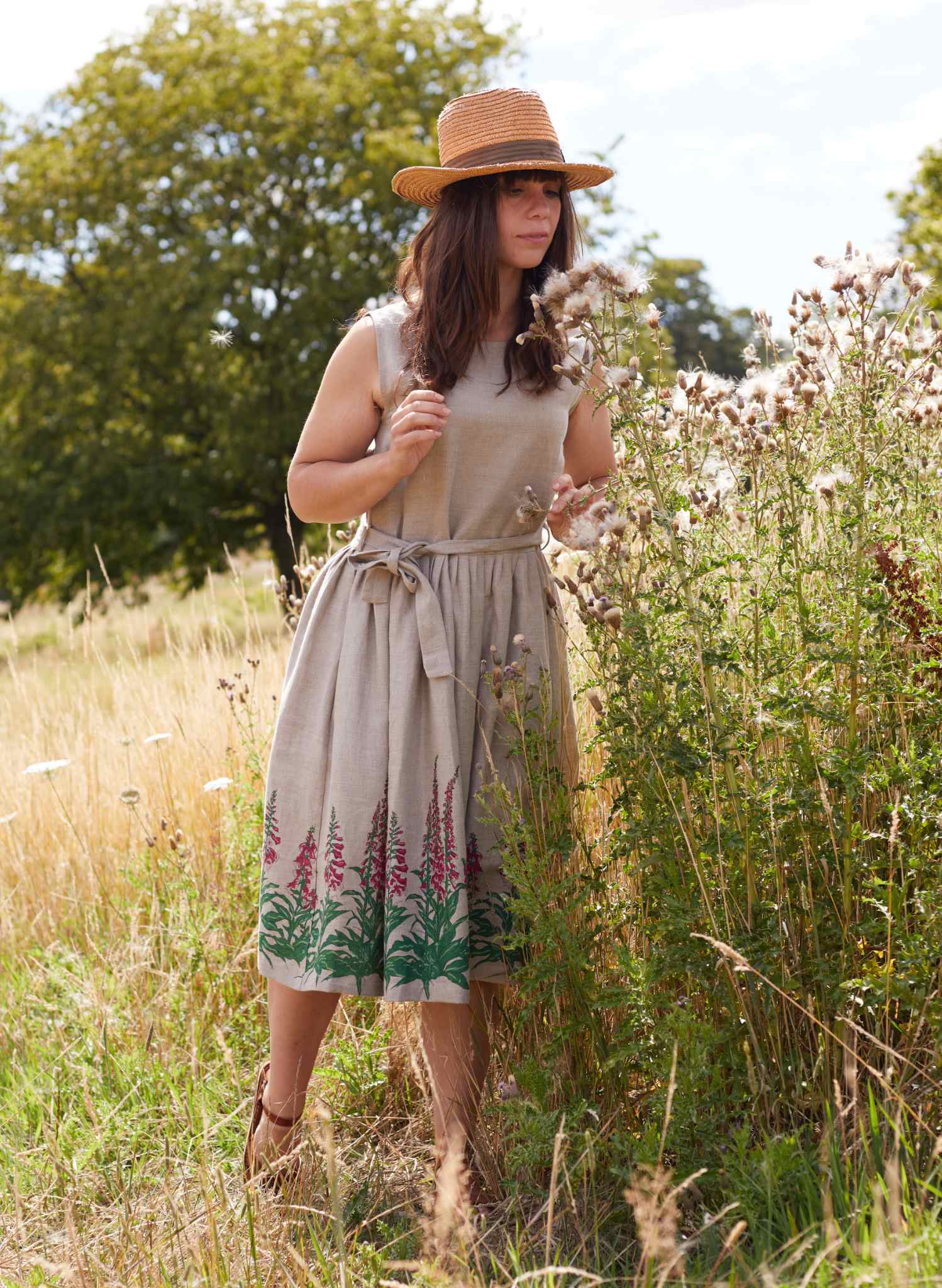 Woman in a wildflower meadow wearing a linen dress with foxgloves in its print
