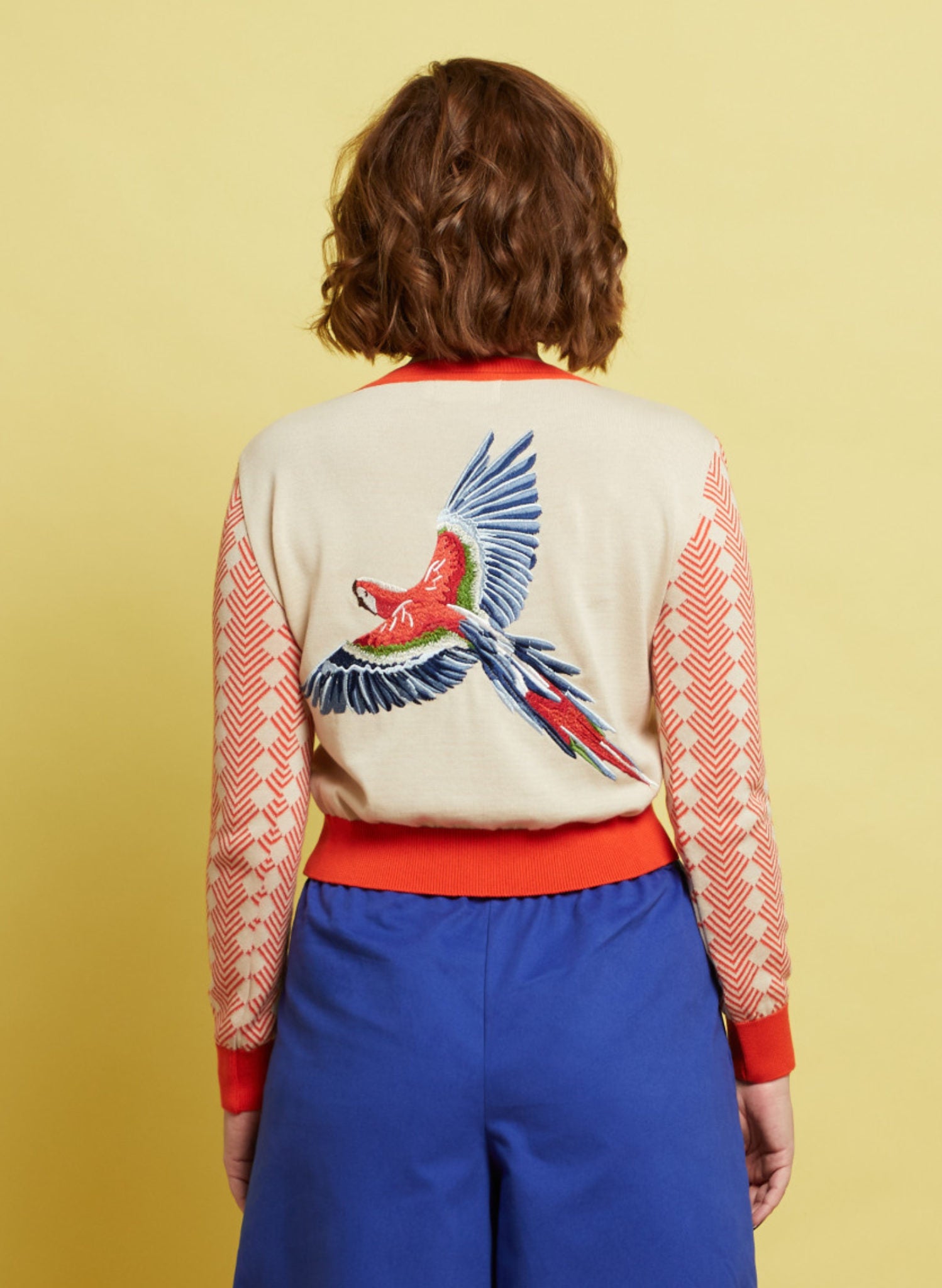 Women's cotton long sleeve cardigan  with large parrot embroidery. In cream white and coral pink.