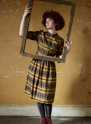 100% Tencel vintage-style gold and black knee-length belted shirt dress with 3/4 length sleeves, pockets, and a deco feather print