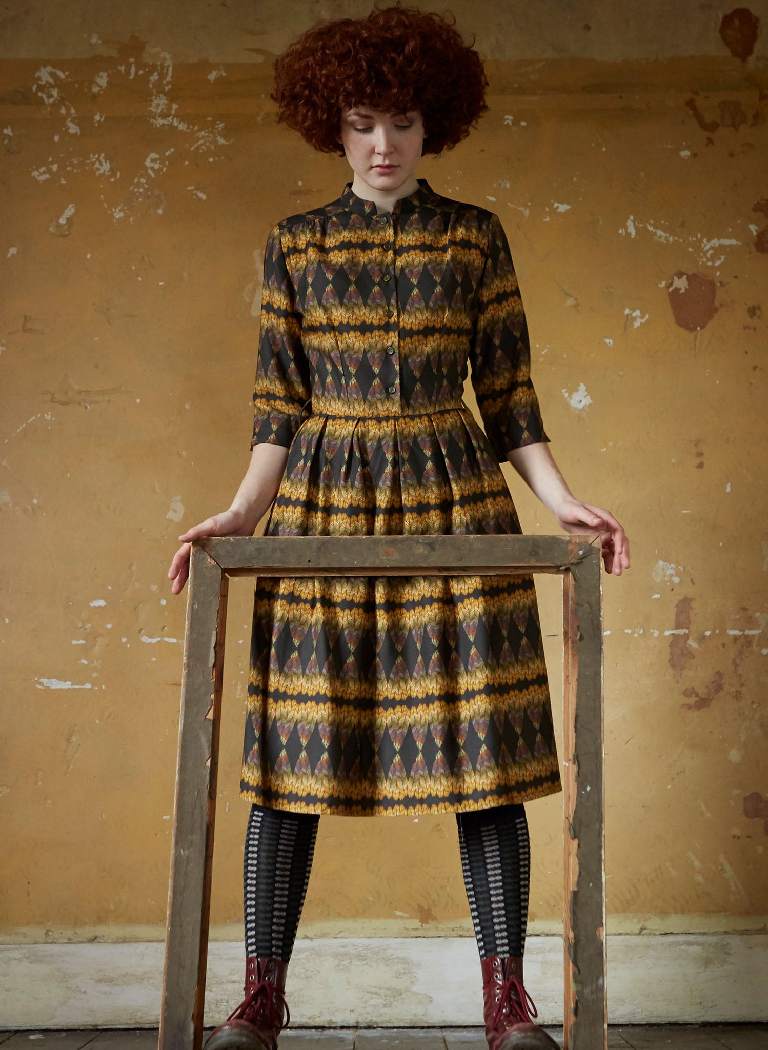 100% Tencel vintage-style gold and black knee-length belted shirt dress with 3/4 length sleeves, pockets, and a deco feather print