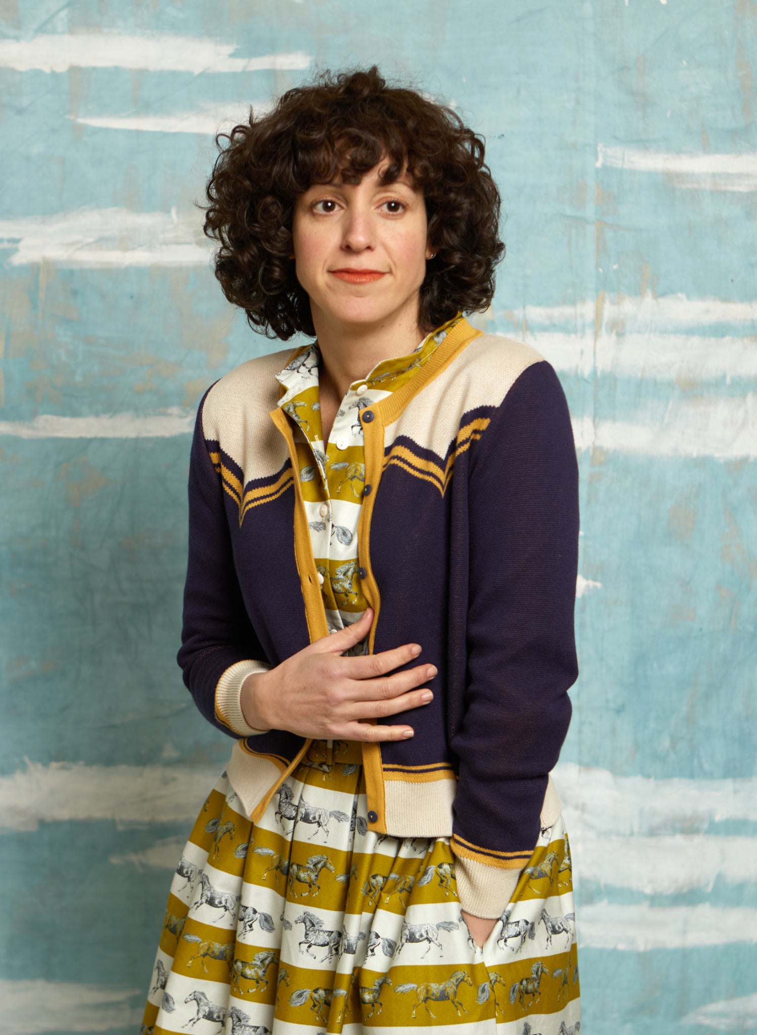 vintage style organic cotton knit cardigan in navy, white, and mustard with horse in the back