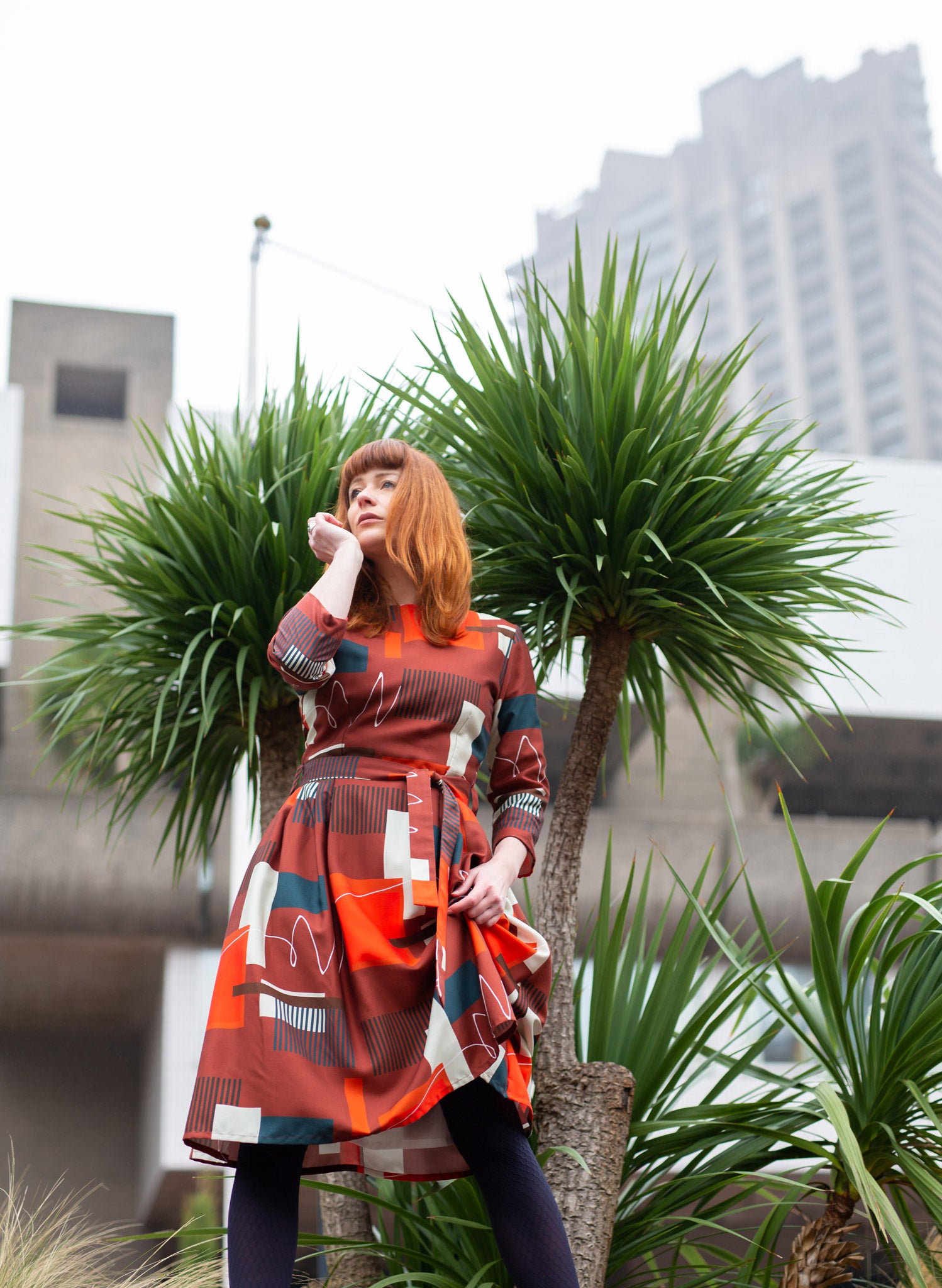 100% Tencel red, navy, and white knee-length dress with a tie-waist belt, 3/4 length sleeves, pockets, v-neck back, and abstract barbican print