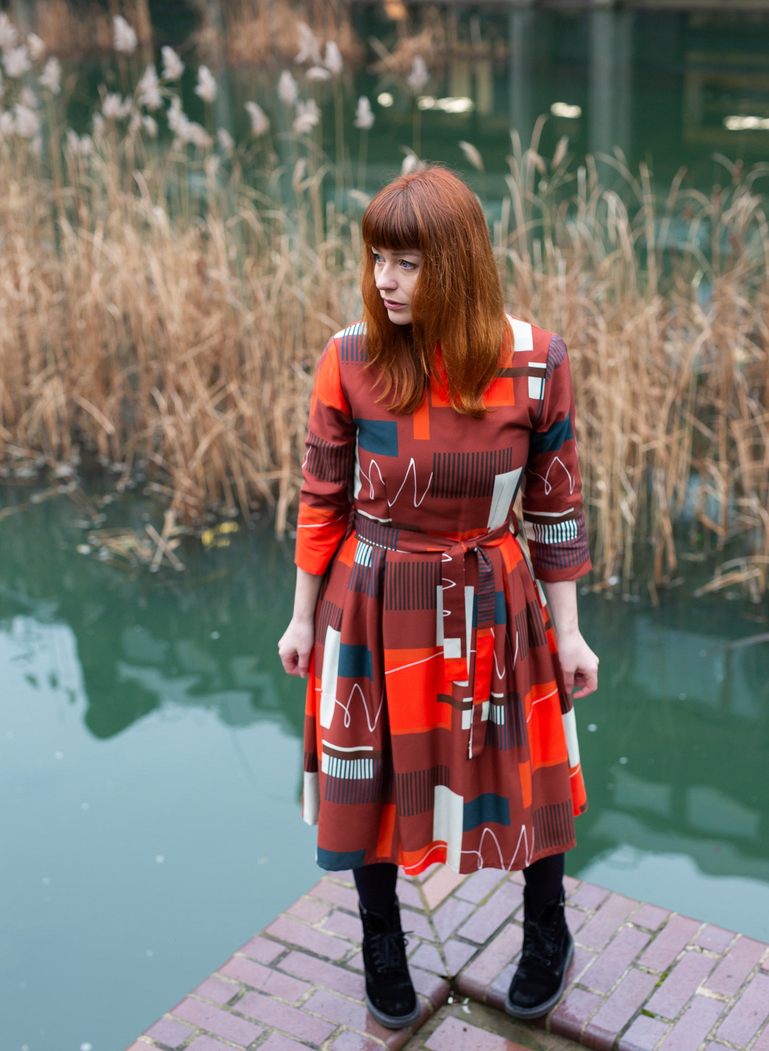 100% Tencel red, navy, and white knee-length dress with a tie-waist belt, 3/4 length sleeves, pockets, v-neck back, and abstract barbican print