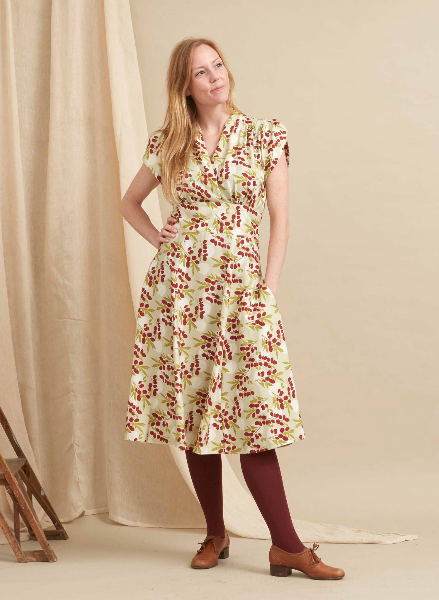 Short sleeve 1940s style mid length dress with colourful print of damson in dark red, green and white